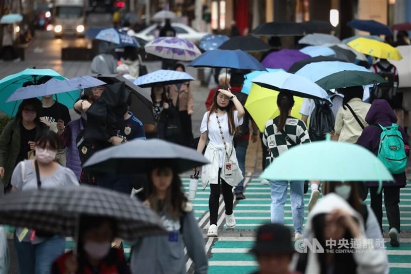 People holding umbrellas cross a street in New Taipei’s Banqiao District amid the recent rainy weather in northern Taiwan. CNA file photo