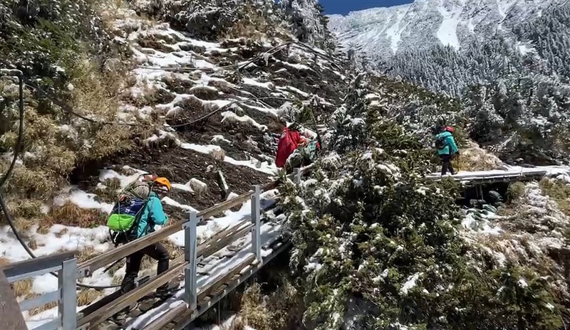 Search and rescue personnel scale Yushan on Sunday to reach the remains of two hikers who fell 380 meters down a steep, icy slope on the peak on Saturday. Photo courtesy of Nantou County Fire Bureau