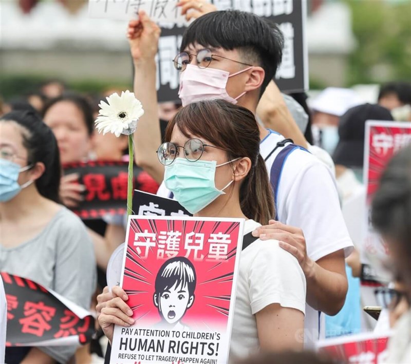 Participants at Saturday’s rally in Taipei hold flowers and signs advocating child protection. CNA photo May 10, 2025