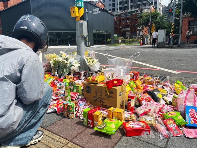 Piles of flowers, snacks and offerings lined the roadside near the site of a fatal car crash in New Taipei's Sanxia District. CNA photo May 20, 2025