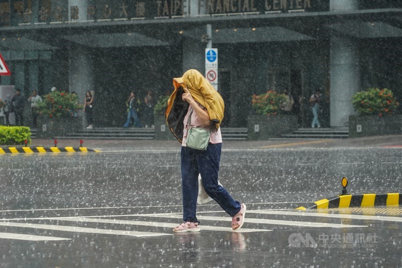 A woman shields her head from the rain while crossing a street in Taipei on Monday. CNA photo June 9, 2025