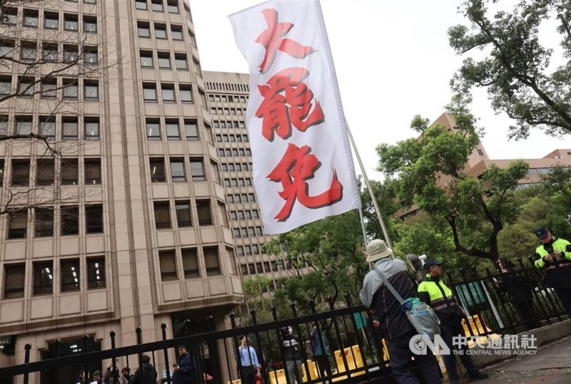 A man holds a large banner that reads "mass recall" in front of the Central Election Commission building in Taipei. CNA file photo
