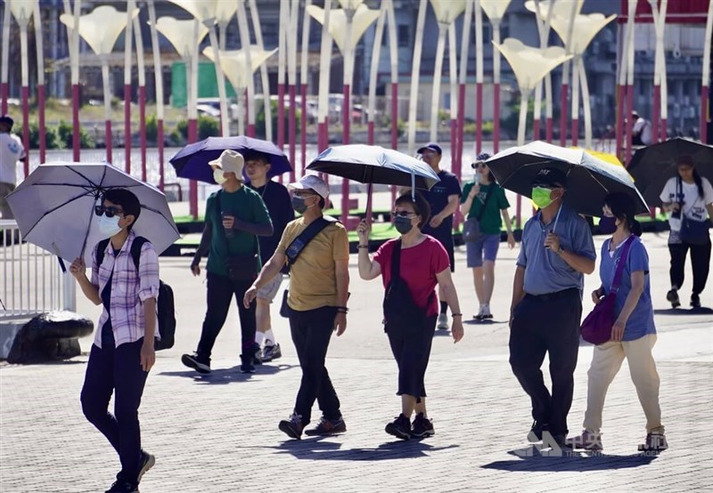 Visitors to Kaohsiung walk under the sun with umbrellas to avoid the heat. CNA file photo