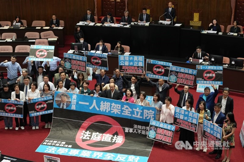 DPP lawmakers hold various signs oppossing the streaming of court hearings. CNA photo June 27, 2025