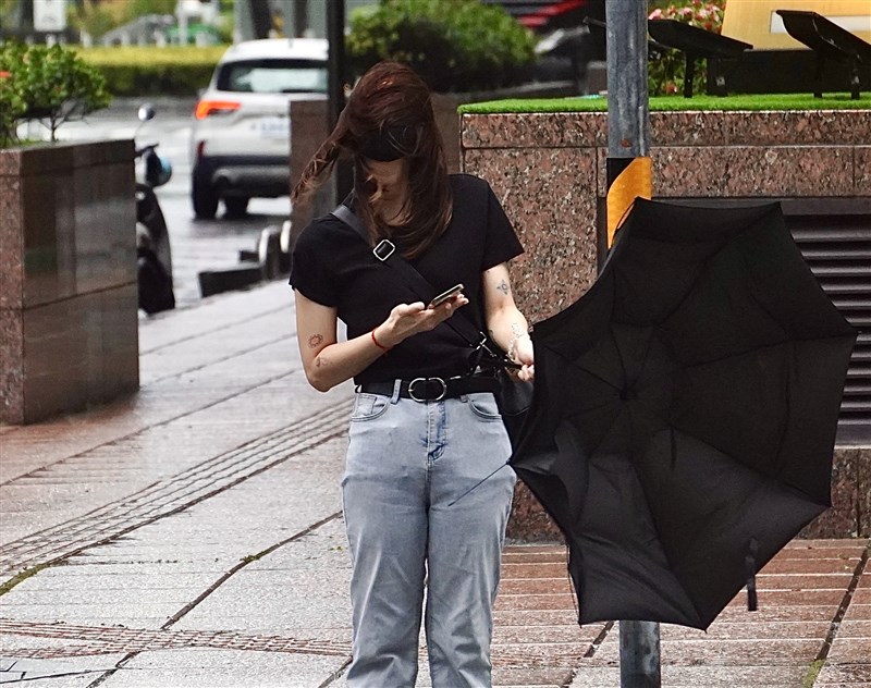 As Typhoon Danas approaches, a passerby on a Kaohsiung street on Sunday struggles against strong winds, with her umbrella blown inside out. CNA photo July 6, 2025