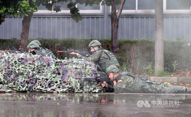 Soldiers remain crouched with their assault rifles behind a camouflaged barrier. CNA photo July 11, 2025