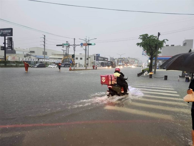 A food delivery driver on a motorcycle braves a flooded intersection in Tainan on Saturday. (Courtesy of Tainan Fire Department)