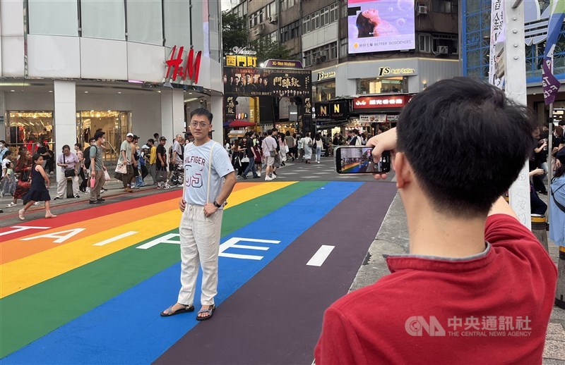 A tourist poses for a photo on the newly repainted “Rainbow Six.” CNA photo Aug. 9, 2025