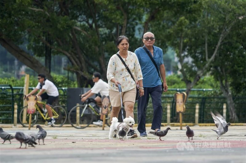 A man and a woman walk their dog in a park in Taipei’s Guandu area. CNA file photo
