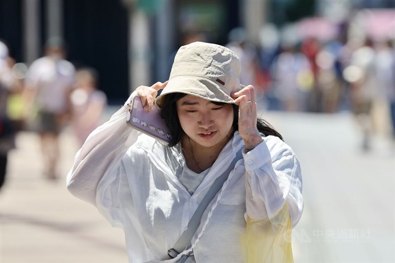 A pedestrian on a Taipei street shields herself from the sun with a hat on Saturday. CNA photo Aug. 16, 2025
