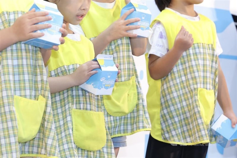 Elementary school students hold milk cartons at a press event of Taipei's Department of Education in Taipei on Monday. CNA photo Aug. 18, 2025.