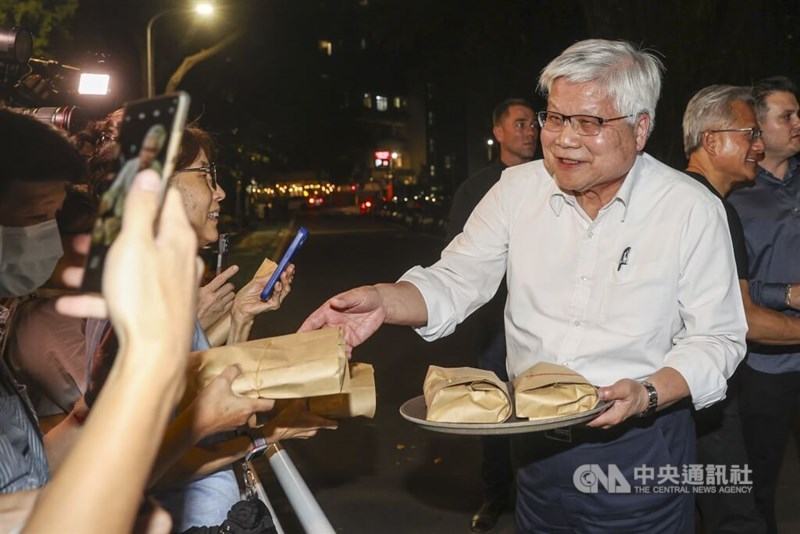 TSMC Chairman and CEO C.C. Wei (in white shirt) hands out free meal boxes to reporters outside a restaurant in Taipei on Friday night. CNA photo, Aug. 22, 2025