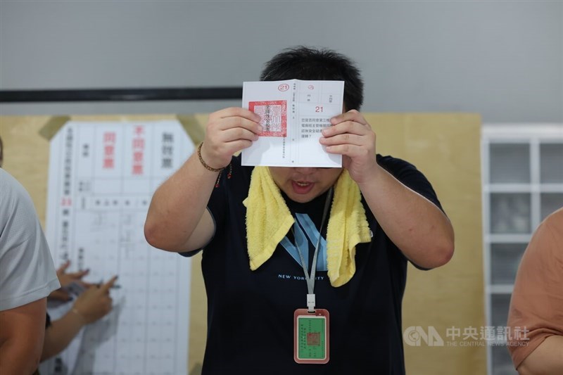 A poll worker displays a ballot as votes are being counted. CNA photo Aug. 23 2025