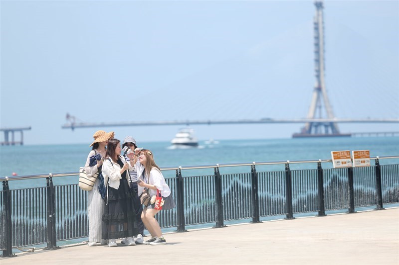 A group of visitors to New Taipei's Tamsui River take a photo at the riverside on Sunday. CNA photo Aug. 24, 2025