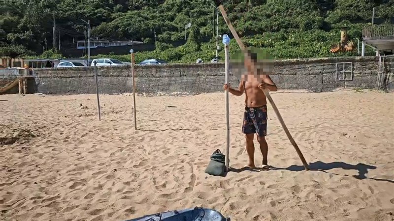 A man sticks a pole in the sand to set up a vending stall at Keelung City's Dawulun Beach on Sunday. Photo courtesy of a private contributor Aug. 31, 2025