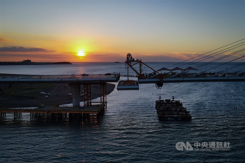 The last piece of the Danjiang Bridge dangles above the Tamsui River as the sun sets on Monday. CNA photo Sept. 15, 2025