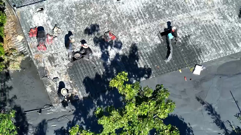 A drone shot captures rescuers on the roof of a nearly submerged house in Guangfu Township, bailing water out with buckets. Photo courtesy of Pingtung County Fire Bureau Sept. 27, 2025