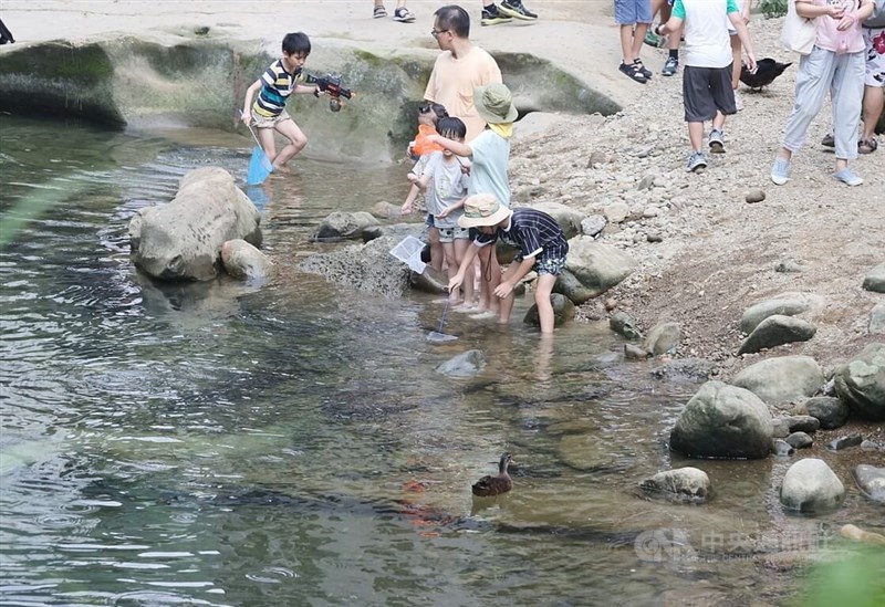 Children wade into the river beside Shiding Old Street and splash each other with water guns on Monday. CNA file photo