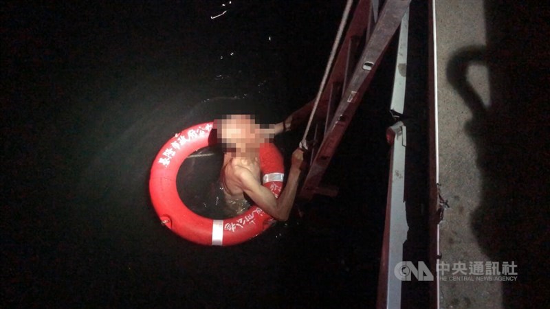 A 60-year-old man surnamed Wang reaches for the ladder after being asked to return ashore at Keelung Harbor, Keelung City, on Tuesday. CNA photo Oct. 7, 2025