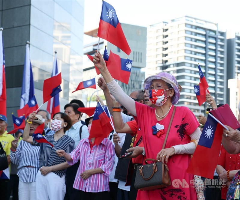 Participants at the KMT's flag-raising ceremony raise national flags to show their support in Taipei on Friday. CNA photo Oct. 10, 2025