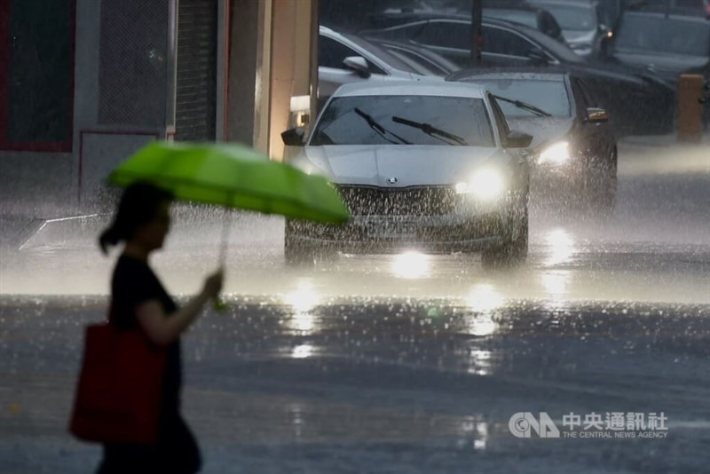 A woman crosses a street in Taipei's Xinyi District amid heavy rainfall. CNA file photo