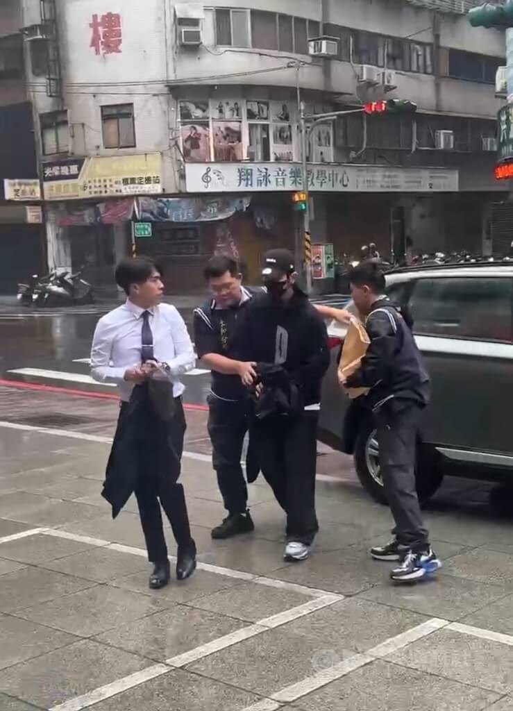 Entertainer Hsiu Chieh-kai (second right) is brought into the New Taipei Police Yonghe Branch on Tuesday. Photo courtesy of the local authority Oct. 21, 2025