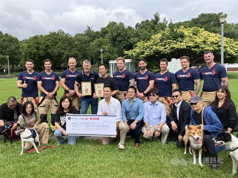 Australian firefighters pose with dogs adopted through Dog Home Taiwan and their owners at Taipei Expo Park Monday. CNA photo Oct. 27, 2025