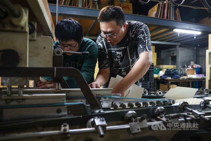 Two workers man a production line in this CNA file photo