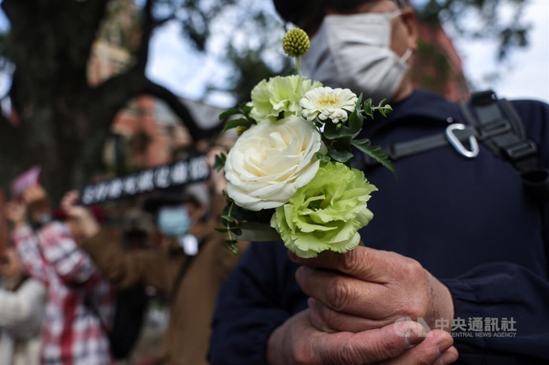 A participant of the Sunday march holds up flowers in memory of Kai Kai. CNA photo Jan. 11, 2026