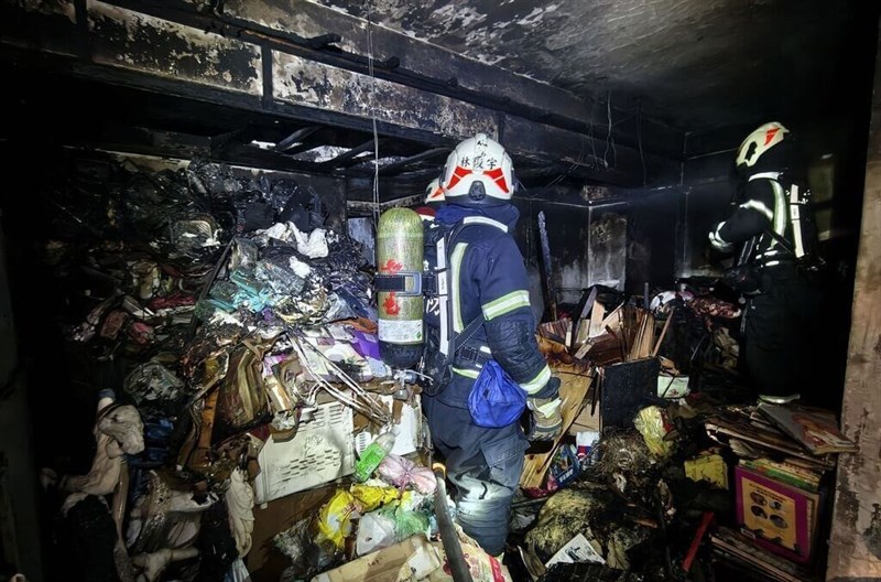 Firefighters inspect the aftermath of the fire that claimed the life of Keelung City Fire Department firefighter Chan Neng-chieh on Thursday. Photo courtesy of local authorities