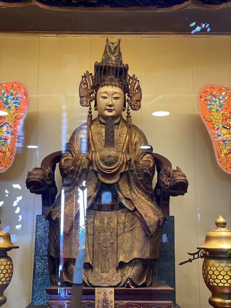 A mountain scops owl perches on a Mazu statue's head at the Quan Hua Temple in Miaoli County, where it remained for two nights and three days, before departing late Monday. Photo courtesy of the Quan Hua Temple