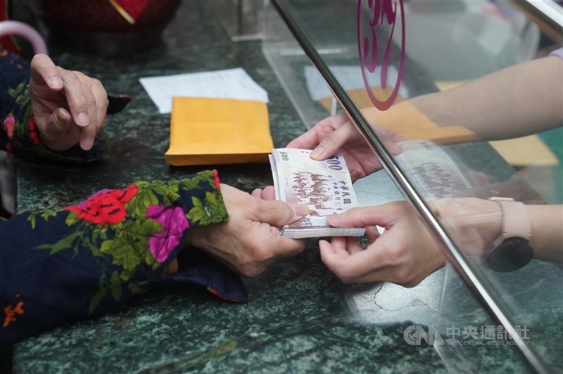 A bank teller services a customer in this CNA file photo