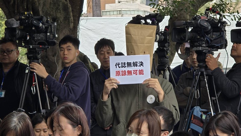A descendant of a victim wears a paper bag over their head while holding a placard at 228 Peace Memorial Park in Taipei on Saturday. CNA photo Feb. 28, 2026