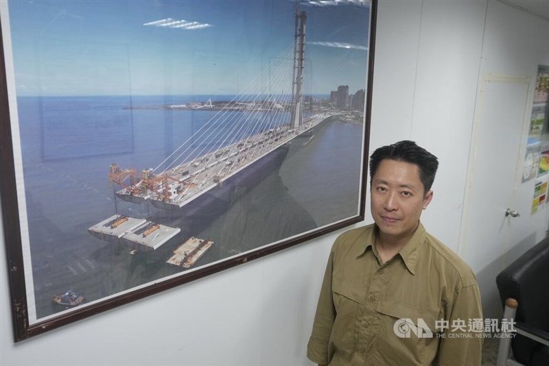 Huang Shao-wei, an associate director at Zaha Hadid Architects, stands next to a framed photo of the under-construction Danjiang Bridge in the project’s site office in Tamsui in late September 2025. CNA photo March 11, 2026