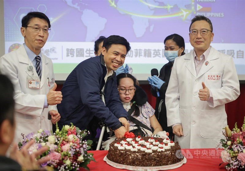 Surgeon Huang Tsai-wang (first left) joins Mark Joseph Radin (second left) and Wendilyn Santoalla (in a wheelchair) as they cut a cake celebrating her successful surgery during a press event at Tri-Service General Hospital in late March. CNA file photo