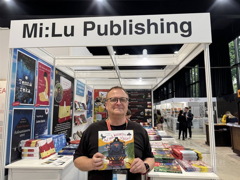 Czech illustrator Tomáš Řízek poses for a photo with his Taiwan-themed picture book "Go, Go, Magical Train" at his publishing company's booth at the Book World Prague fair on Saturday. CNA photo May 19, 2026