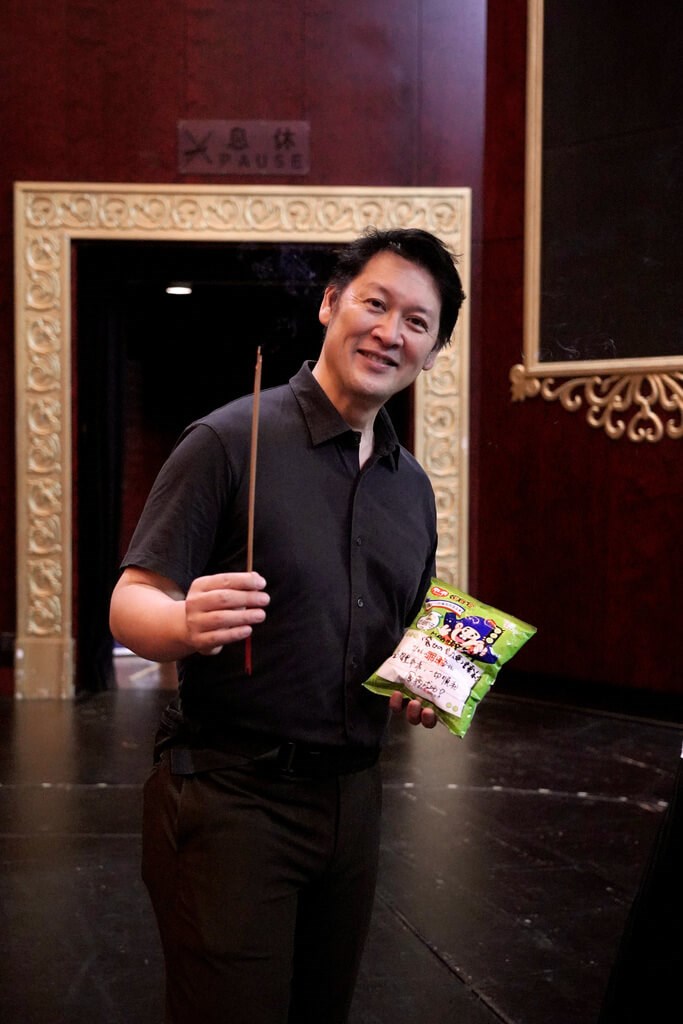 Ryota Kojima, music director of the Kiki's Delivery Service stage musical, holds a stick and a bag of Kuai Kuai puffcorn at the National Theater in Taipei. Photo courtesy of Management of New Arts