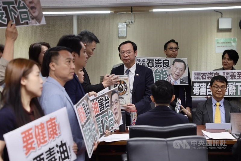 Opposition legislators protest against food safety issues regarding carcinogenic substances in edible oil, presenting a symbolic oil drum to Health Minister Shih Chung-liang (center) at the Legislative Yuan on Wednesday. CNA photo July 8, 2026.