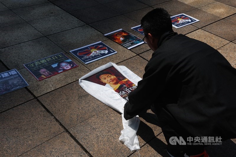 A protester spreads out a photo of late Tibetan activist Lobga Rangzen among other Tibetan figures like the Dalai Lama and Panchen Lama during the demonstration on Sunday. CNA photo Aug. 2, 2026