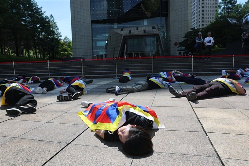Protesters stage a "die-in" outside the Bank of China's Taipei branch, lying on the ground draped in Tibetan flags before rising one by one, on Sunday. CNA photo Aug. 2, 2026