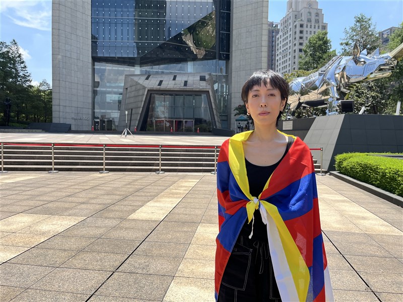 Taiwanese rally participant Panthea Lee poses with a Tibetan flag draped around her shoulders outside the Bank of China’s Taipei branch on Sunday. CNA photo Aug. 2, 2026.