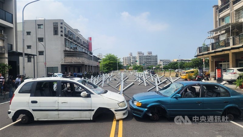 Wheelless vehicles and metal barricades block a road near Kaohsiung International Airport on Thursday during a road barrier deployment drill as part of the annual Han Kuang military exercise. CNA photo Aug. 6, 2026
