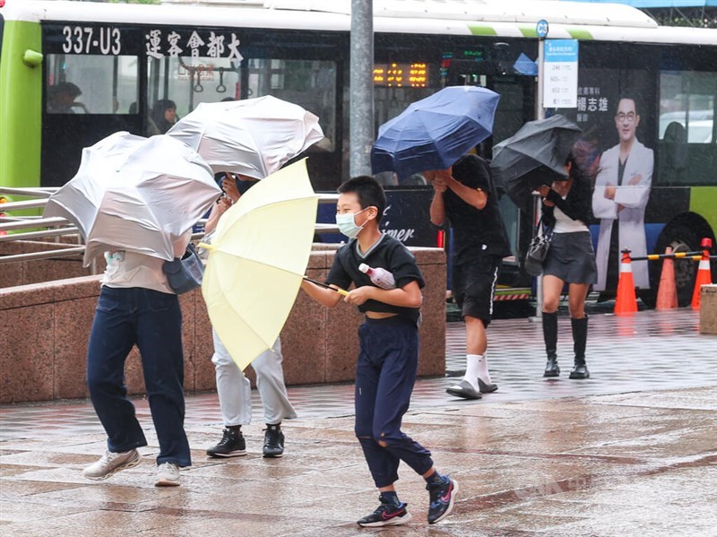 Pedestrians walk on with their umbrellas as a sudden gust of wind sweeps through the streets of Taipei on Sunday. CNA photo Aug. 9, 2026