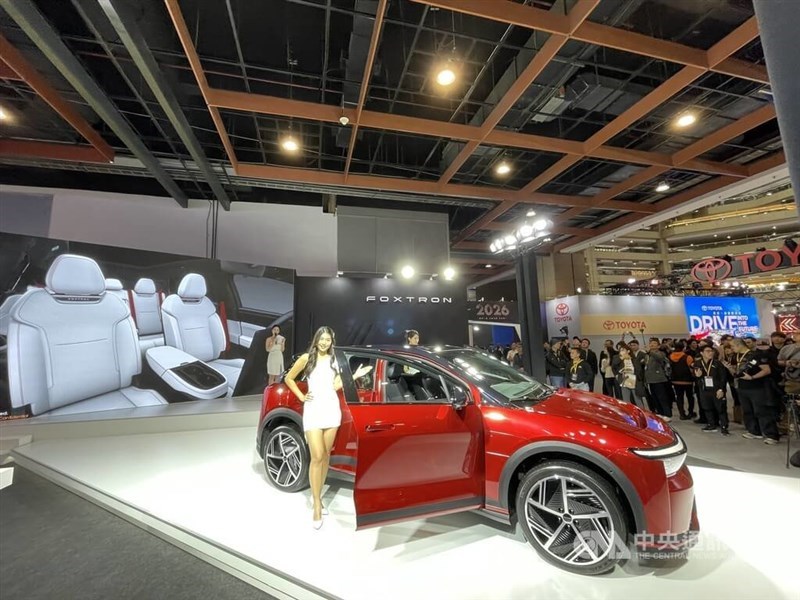 A model poses beside a Foxtron electric vehicle at an auto exhibition in Taipei in December 2025. CNA file photo