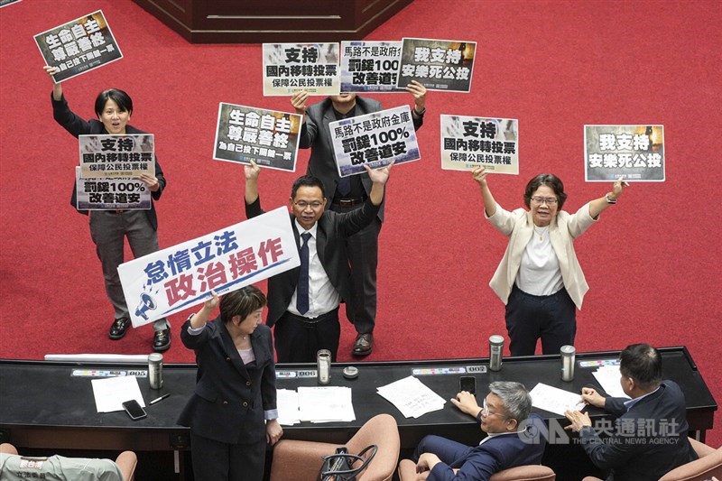 Taiwan People's Party caucus convener Chen Ching-lung (standing, center) leads TPP lawmakers in holding placards supporting referendum proposals while Democratic Progressive Party caucus Secretary-General Fan Yun (front left) holds a sign reading "Lazy legislating, political manipulation" in the Legislative Yuan in Taipei on Friday. CNA photo Aug. 14, 2026