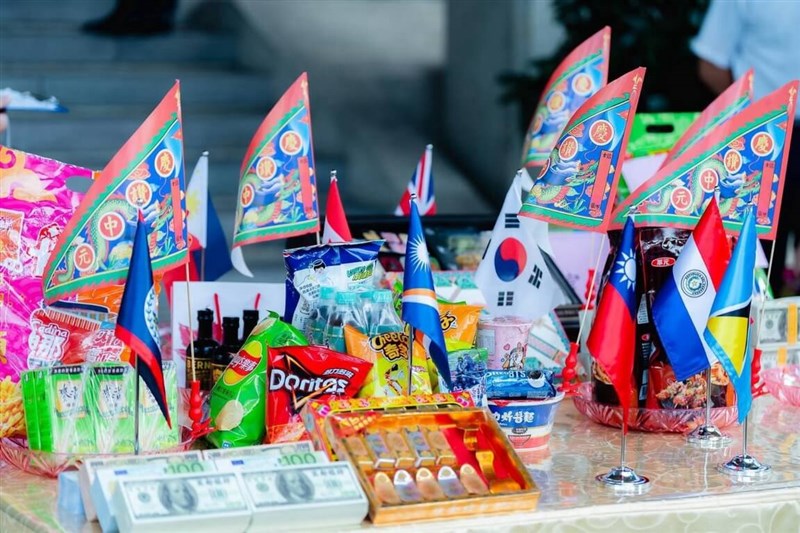 Snacks, beverages, and miniature national flags contributed by diplomatic allies and friendly nations are displayed on a table at a Ghost Festival prayer ceremony hosted by the Ministry of Foreign Affairs in Taipei on Wednesday. Photo courtesy of Ministry of Foreign Affairs