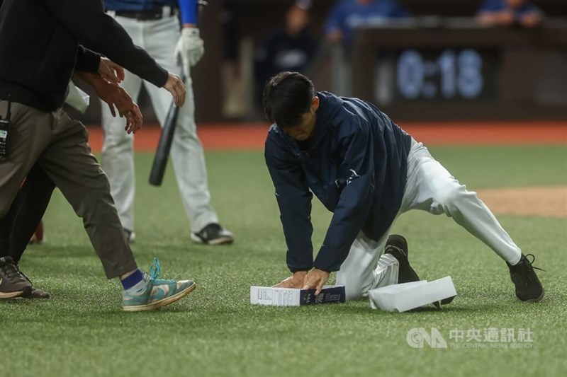 A stadium worker (right) traps a small rat with a cardboard box on the field at Taipei Dome on Wednesday. CNA photo Sept. 10, 2026
