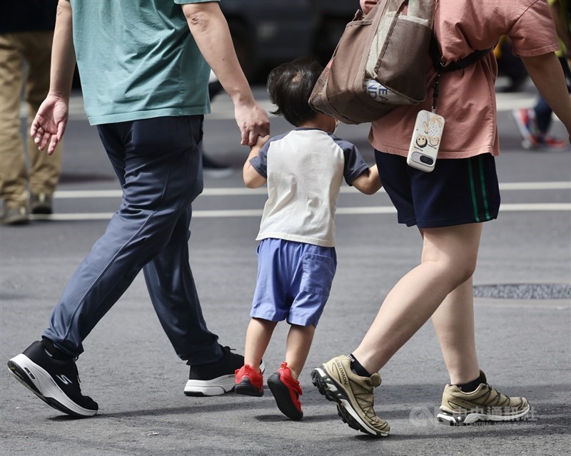Parents walk with a young child along a street in Taipei. CNA photo Sept. 10, 2026