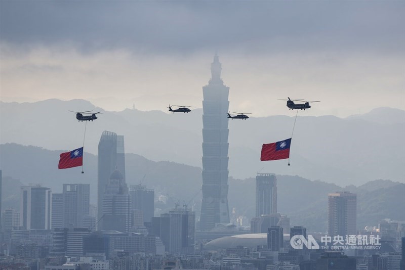 Two CH-47SD Chinook helicopters, each carrying a giant national flag, fly over Taipei with Taipei 101 in the background. CNA photo Oct. 2, 2026
