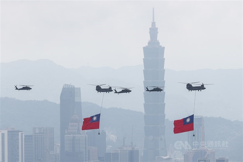 Two Chinook helicopters carrying large Republic of China (ROC) flags fly over Taipei, accompanied by Black Hawk helicopters. CNA photo Oct. 10, 2026